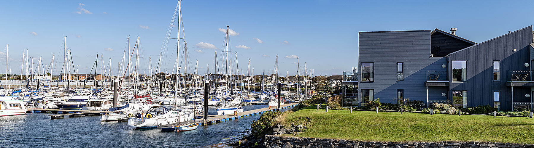 Troon Yacht Haven marina with moored yachts, pontoons and modern waterfront building on Ayrshire coast under clear skies.