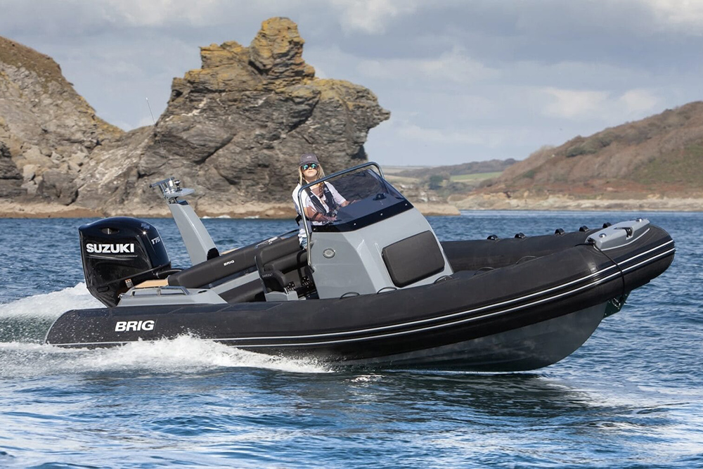 Brig Eagle 6.7 RIB underway with Suzuki outboard, console helm and rocky coastal backdrop
