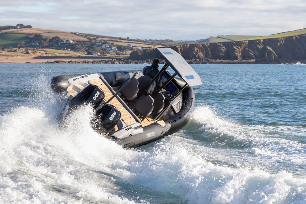 Twisted RIB carving through waves at speed with twin outboards, helm seating and coastal cliffs in the background