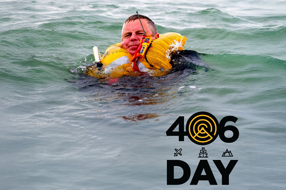 Man floating in open water wearing lifejacket with activated PLB, demonstrating marine distress beacon use for 406Day