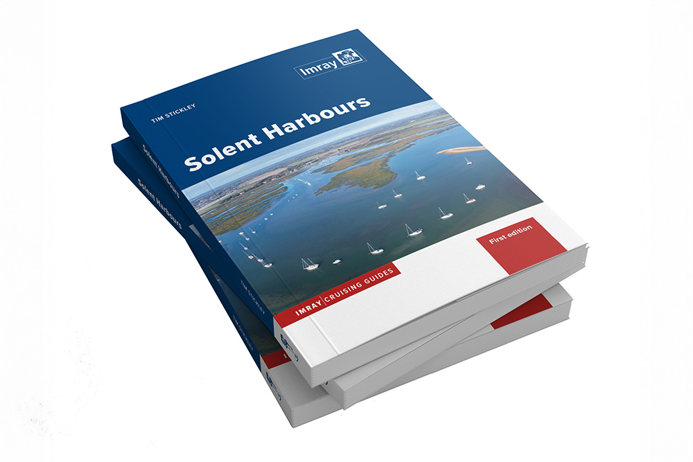 Stacked copies of Imray Solent Harbours cruising guide first edition showing cover with aerial view of Solent anchorage and sailboats