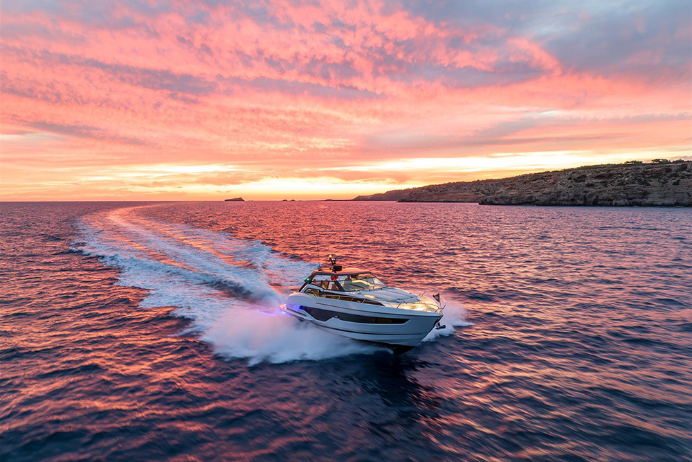 Sunseeker Superhawk 55 performance boat at speed during sunset, carving across open water with illuminated wake.