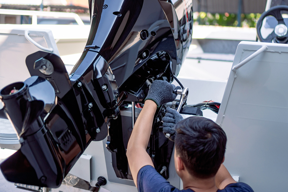 Engineer installing an outboard motor onto a motorboat