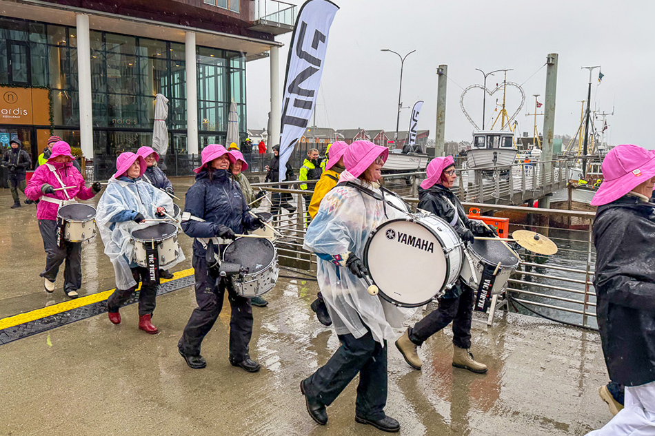 Members of a band playing instruments in wet weather clothing