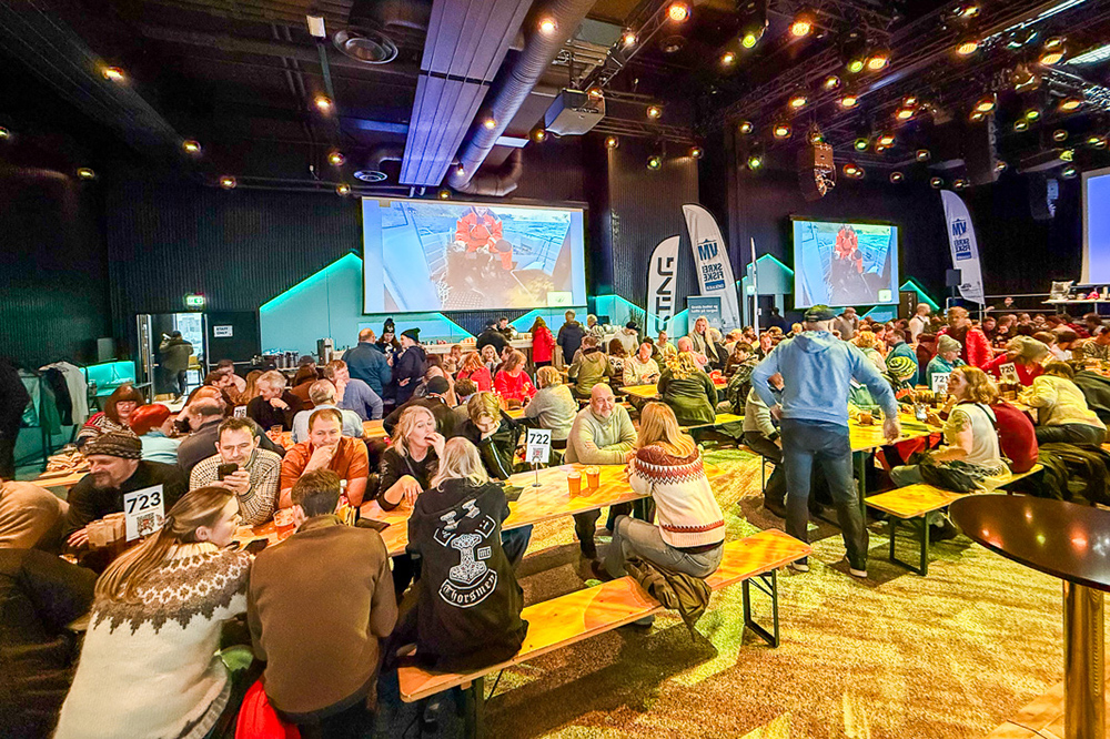Award winning ceremony with teams sat at tables and TV screens in the background