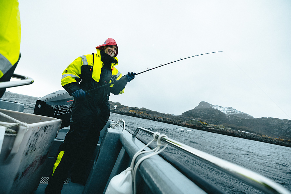 Fisherman holding fishing rod over side of boat