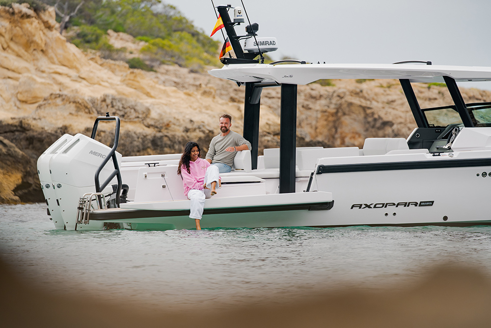 Couple relaxing aboard the Axopar 38 Sun Top at anchor with twin Mercury outboards and open cockpit seating