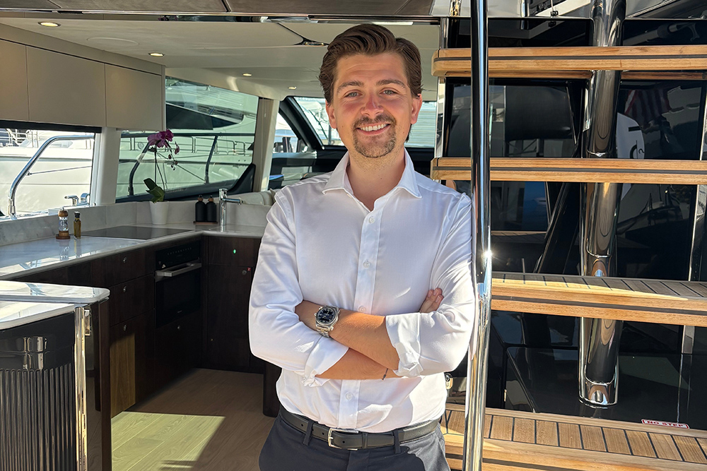 Fairline representative aboard luxury yacht interior beside teak stairs and galley during warranty announcement
