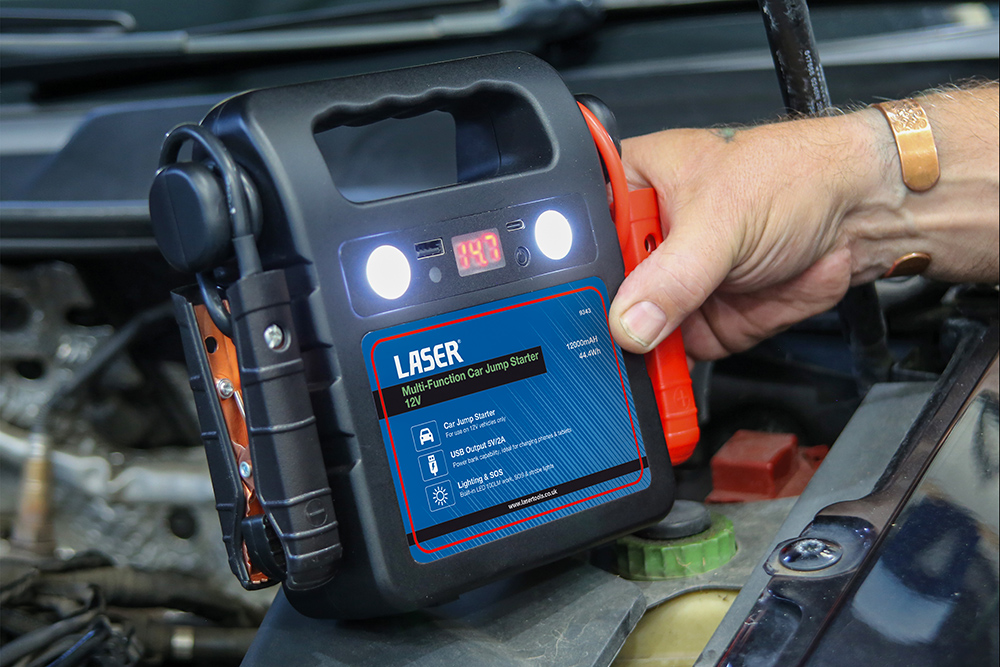 Laser Tools 12V portable jump starter connected to a vehicle battery during emergency engine start procedure.