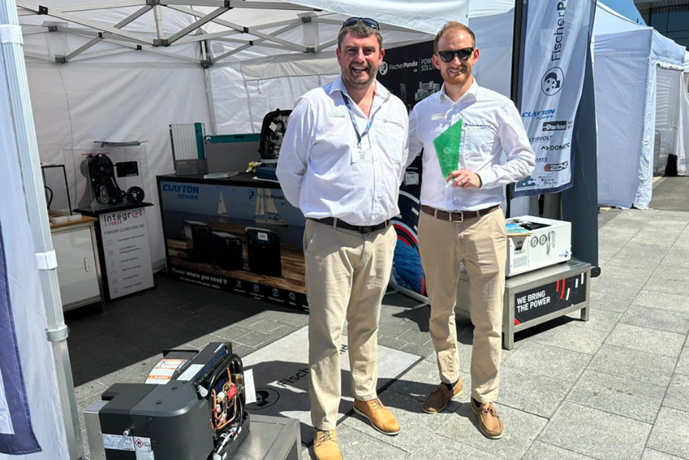 Fischer Panda UK team at South Coast Green Tech Boat Show stand holding sustainability award in Southampton.