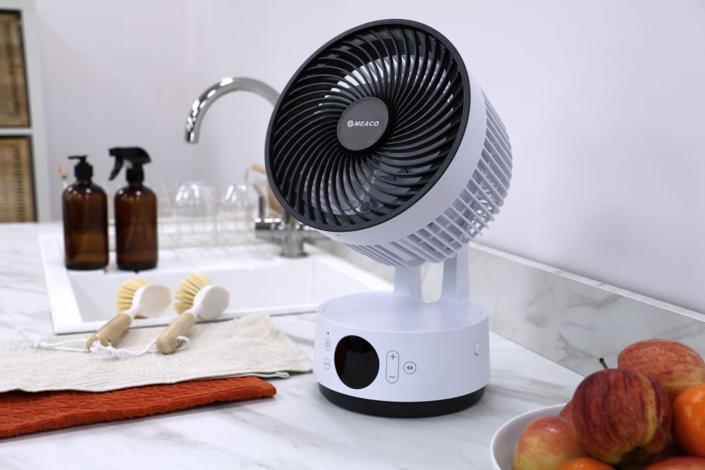 Meaco Sefte portable battery air circulator on a worktop beside fruit and cleaning brushes.