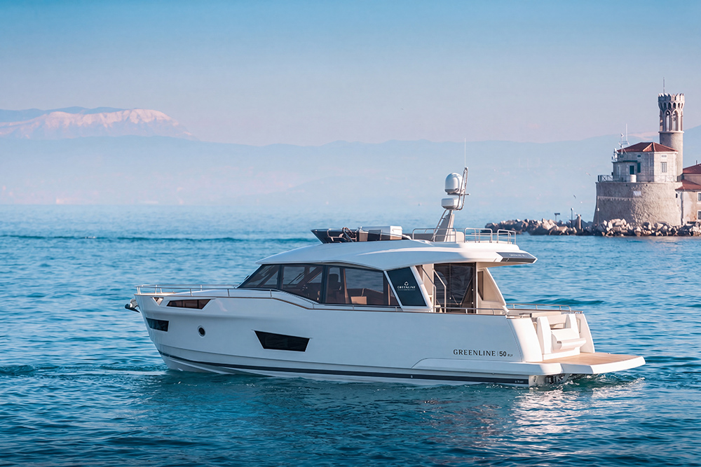 Greenline 50 flybridge yacht cruising near Portorož waterfront on calm blue water.