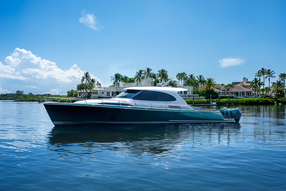 Palm Beach GT50 RS outboard yacht cruising on calm water beside waterfront homes and palm trees