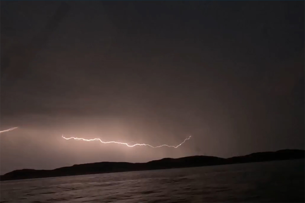ightning over dark Cemaes Bay waters during Moelfre RNLI thunderstorm rescue incident.