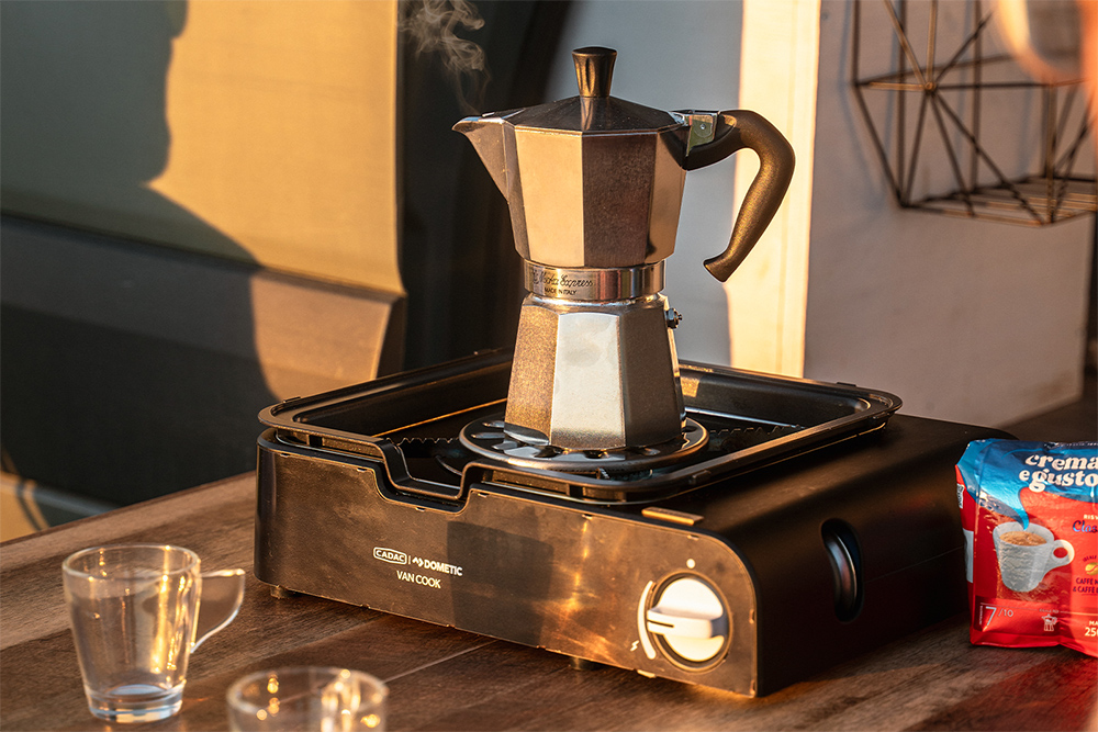 Dometic Van Cook portable gas cooker brewing coffee outdoors at sunset for vanlife camping cuisine.