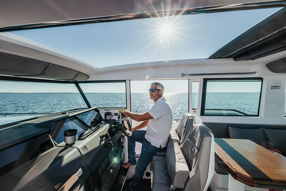 Man at the helm of an Axopar cabin boat, cruising on open water