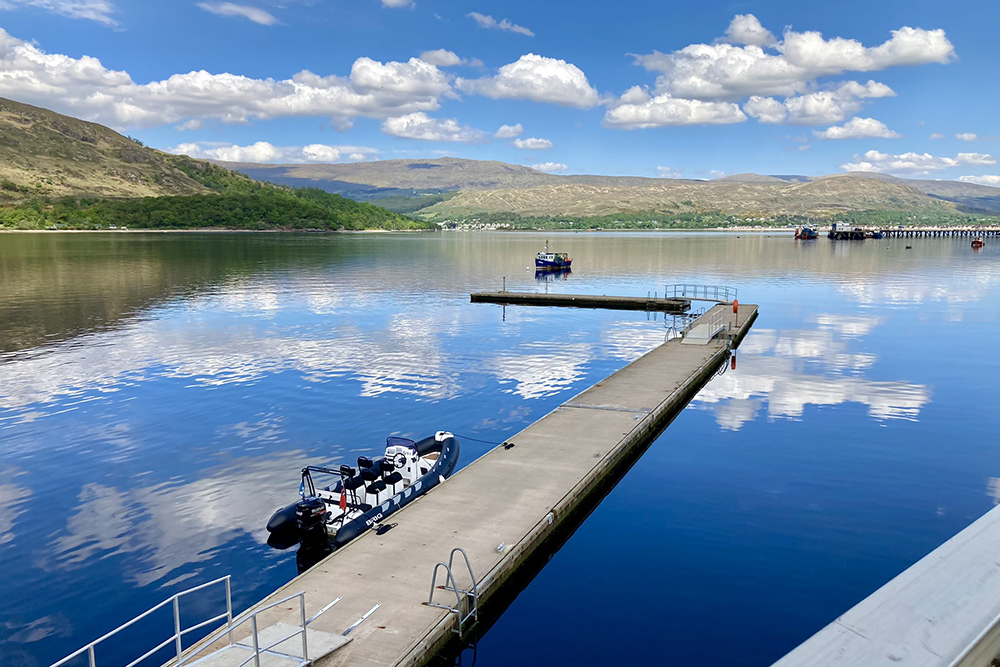 BRIG RIB moored at Fort William pontoons on calm Loch Linnhe with Highland hills reflected in the water
