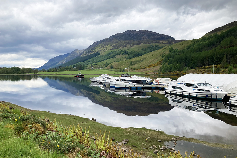 Boats moored at Gairlochy on the Caledonian Canal, with Highland hills reflected in still water