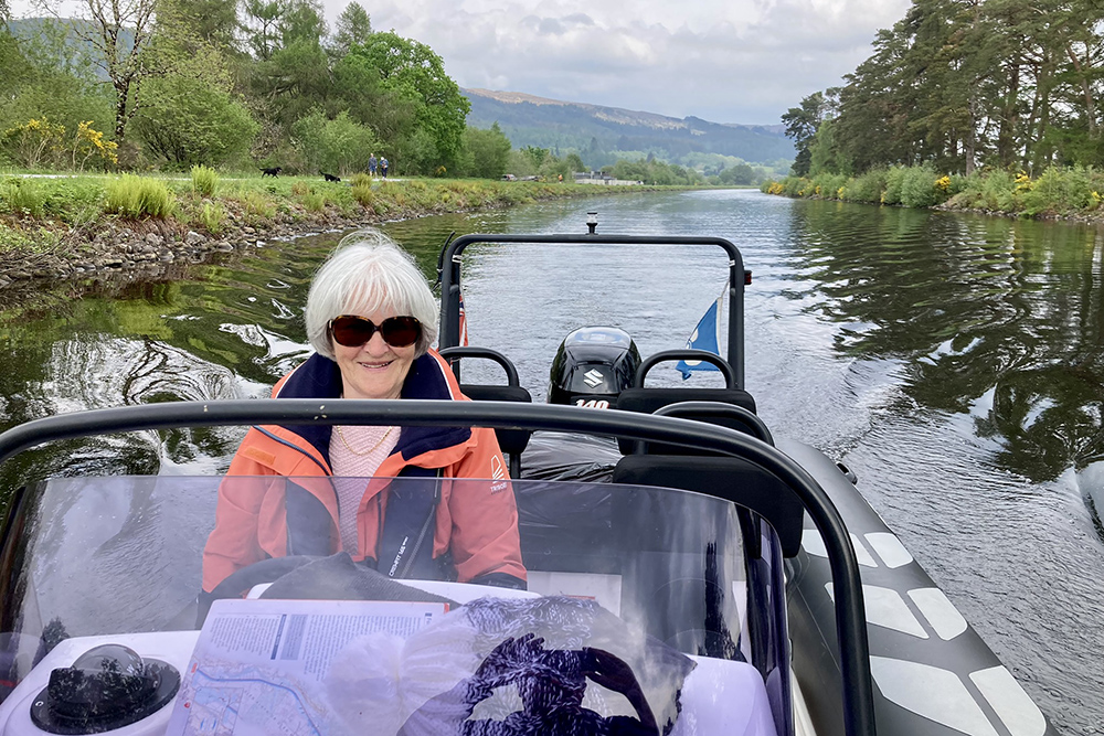 RIB cruising the Caledonian Canal with crew at the helm and Highland scenery around