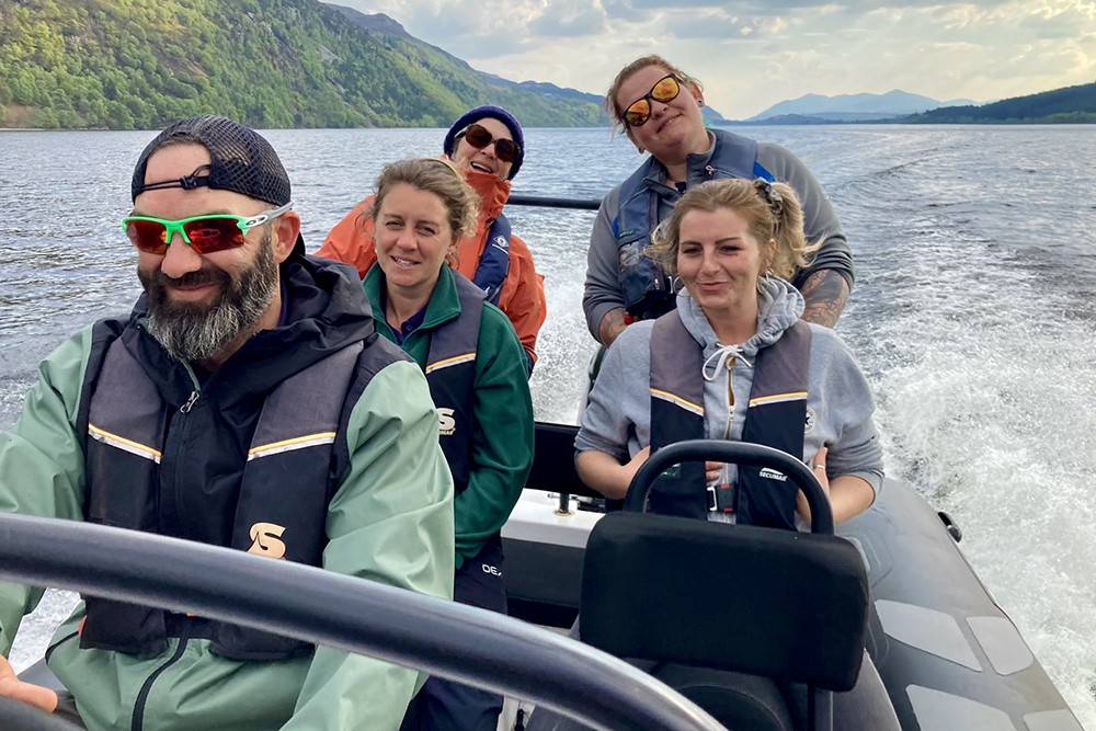 Group enjoying a RIB ride on Loch Ness, with Highland shoreline and wake behind them