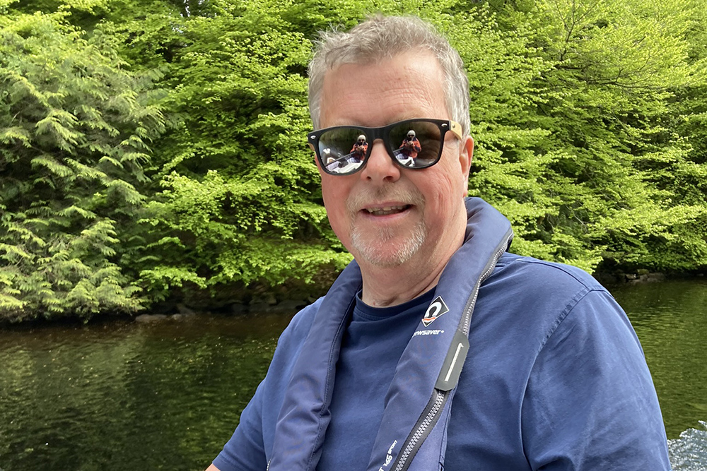 RIB skipper on the Caledonian Canal, with woodland and water reflected in sunglasses