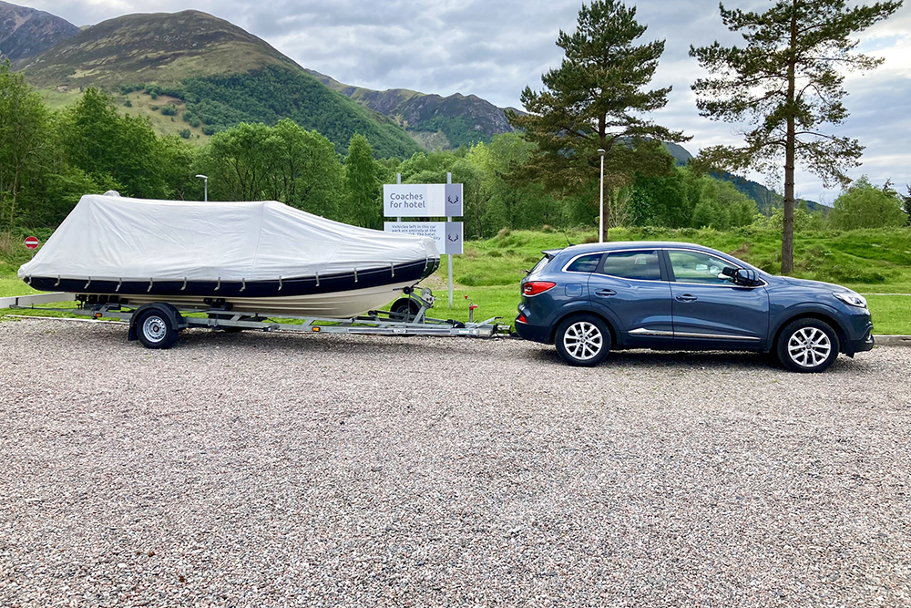 Car towing a covered BRIG RIB on a trailer through the Highlands after a Loch Ness adventure