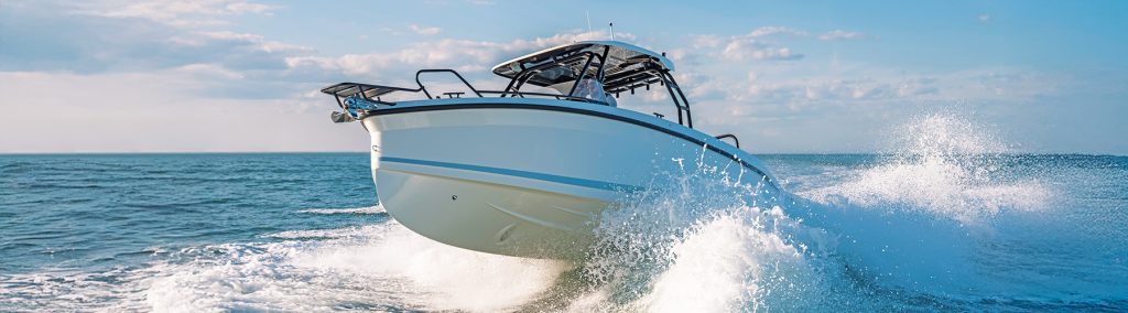 Navan T30 T-top sportscruiser powering through a white wave with blue skies behind
