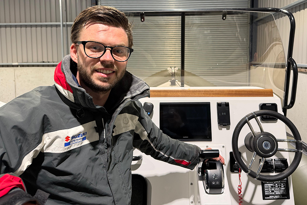 Adam Brennan on his RIB in front of the console with his hand on the throttle