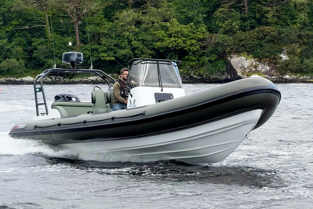 Redbay 850 RIB with green tubes and white hull underway on a grey sea with trees behind