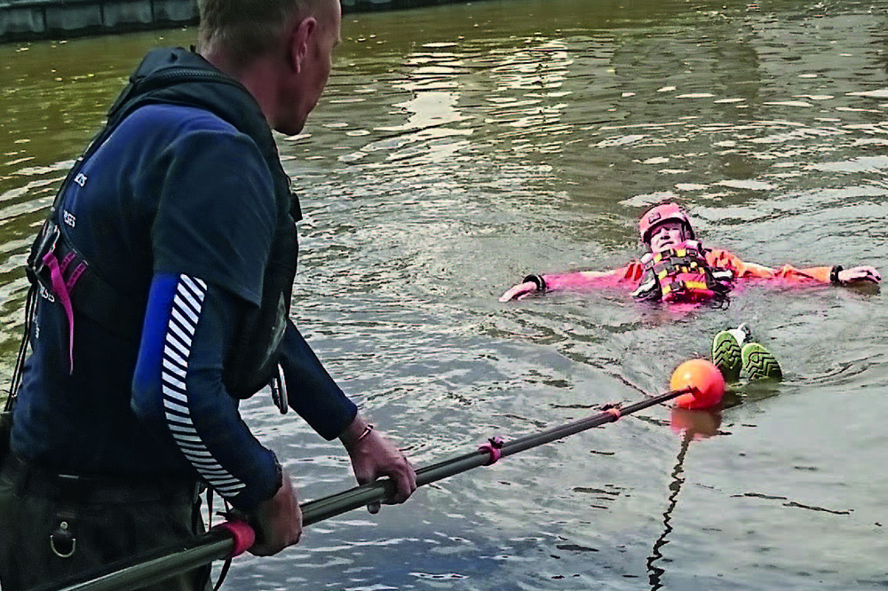 Trainee uses a reach pole to assist a casualty during British Marine practical water rescue training.