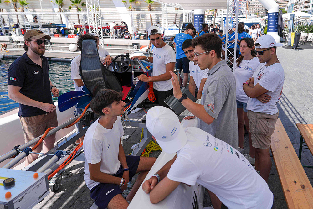 Student teams discuss a prototype boat at the Monaco Energy Boat Challenge paddock.