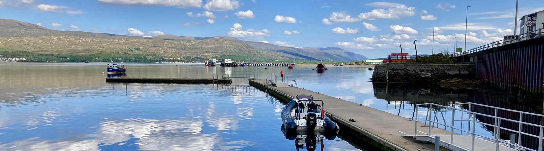 BRIG RIB moored at Fort William pontoons on calm Loch Linnhe beneath Highland hills