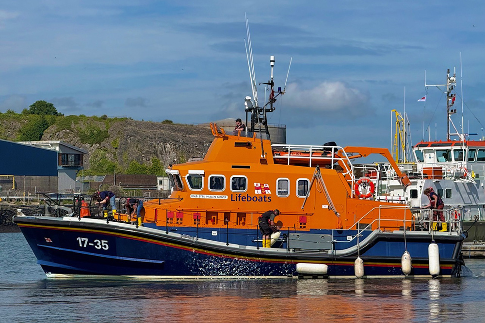RNLI lifeboat crew on display at Plymouth Boat Fest beside harbour workboats.