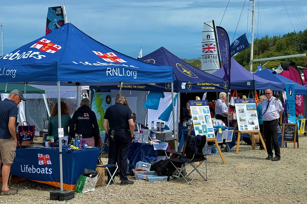 RNLI and marine safety stands at Plymouth Boat Fest with visitors browsing exhibits by the marina.