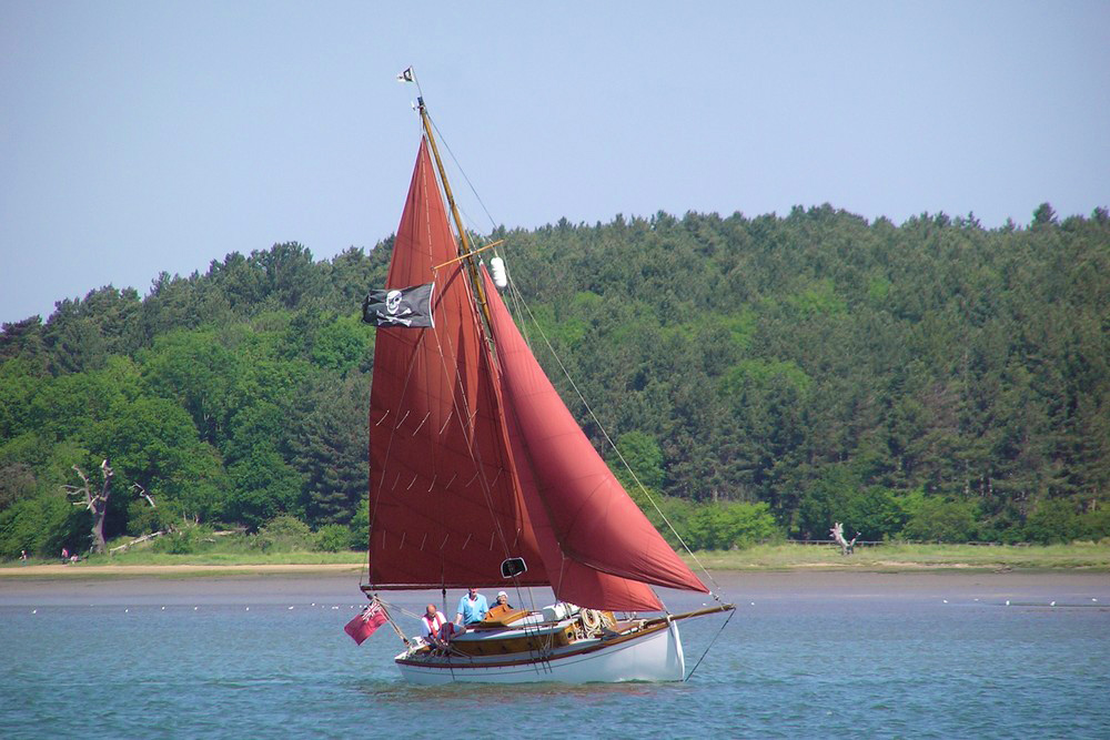 Wooden sailing vessel, the Nancy Blackett, with red sail underway on River Orwell