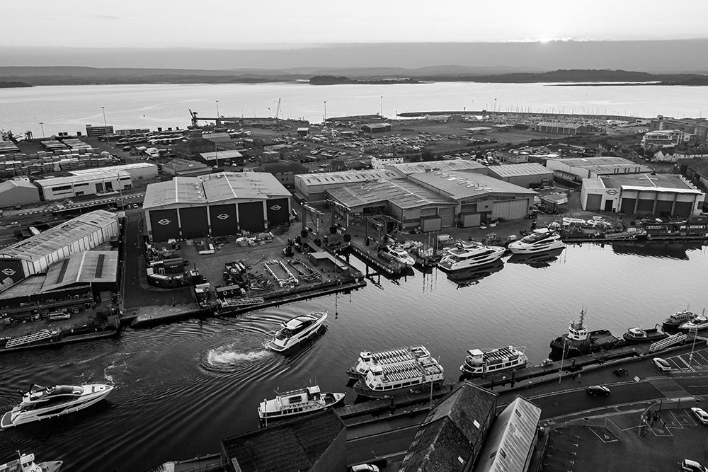 Aerial view of Sunseeker’s waterfront shipyard with luxury motor yachts and production buildings.