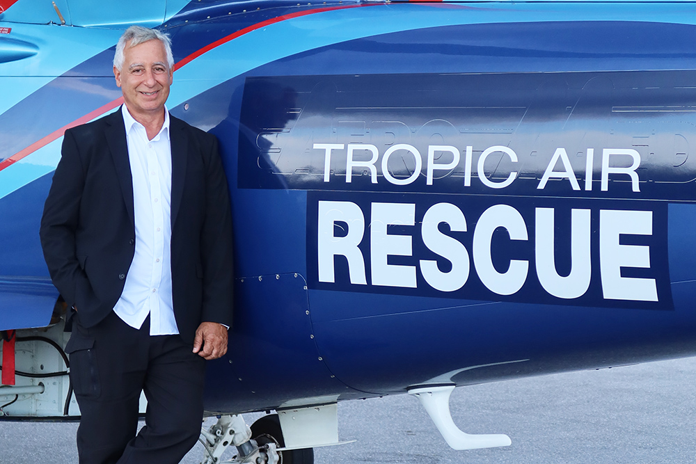 A man beside a Tropic Air Rescue helicopter.