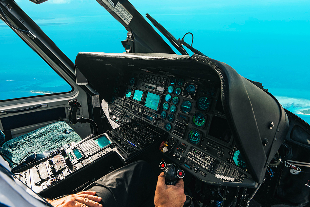 Tropic Air Rescue helicopter cockpit in flight over the Bahamas, showing navigation instruments and flight controls.