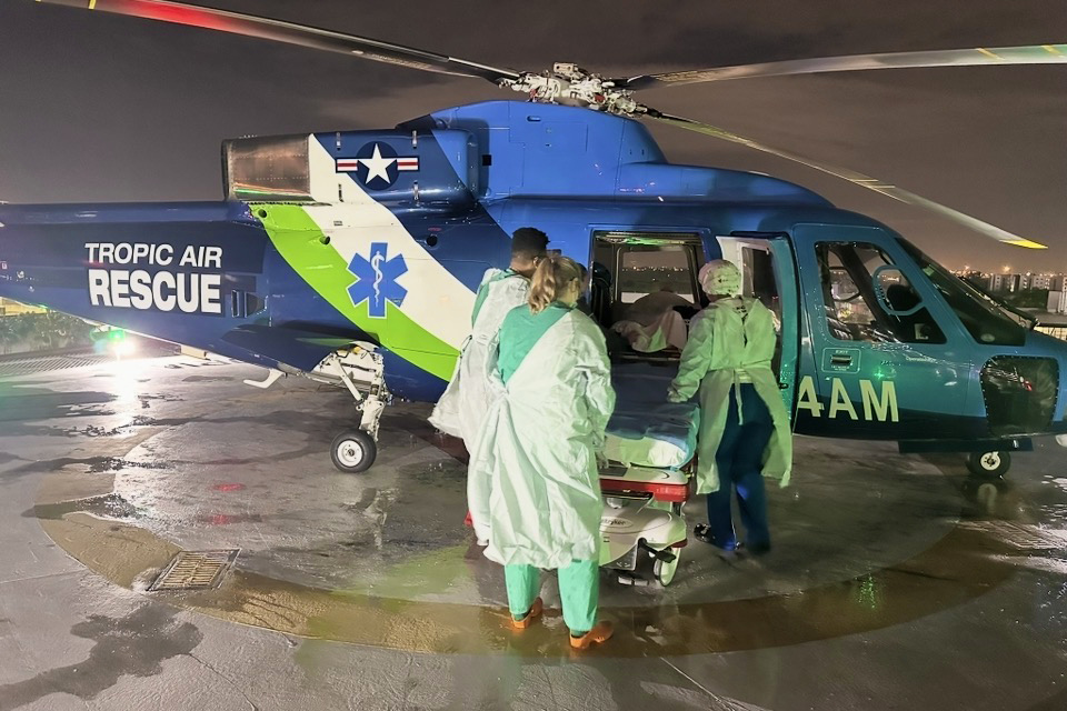 Tropic Air Rescue medical team loading a patient into a helicopter during a night-time emergency evacuation.