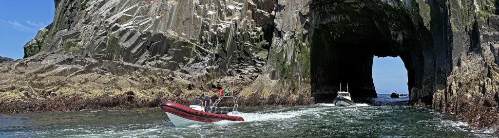 Two RIBs passing through the tunnel of the Bull Rock in Ireland
