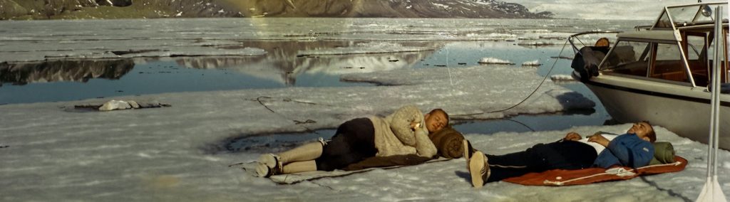 Archive photo of 3 men lying on ice sheets next to vintage Nordkapp in 1970