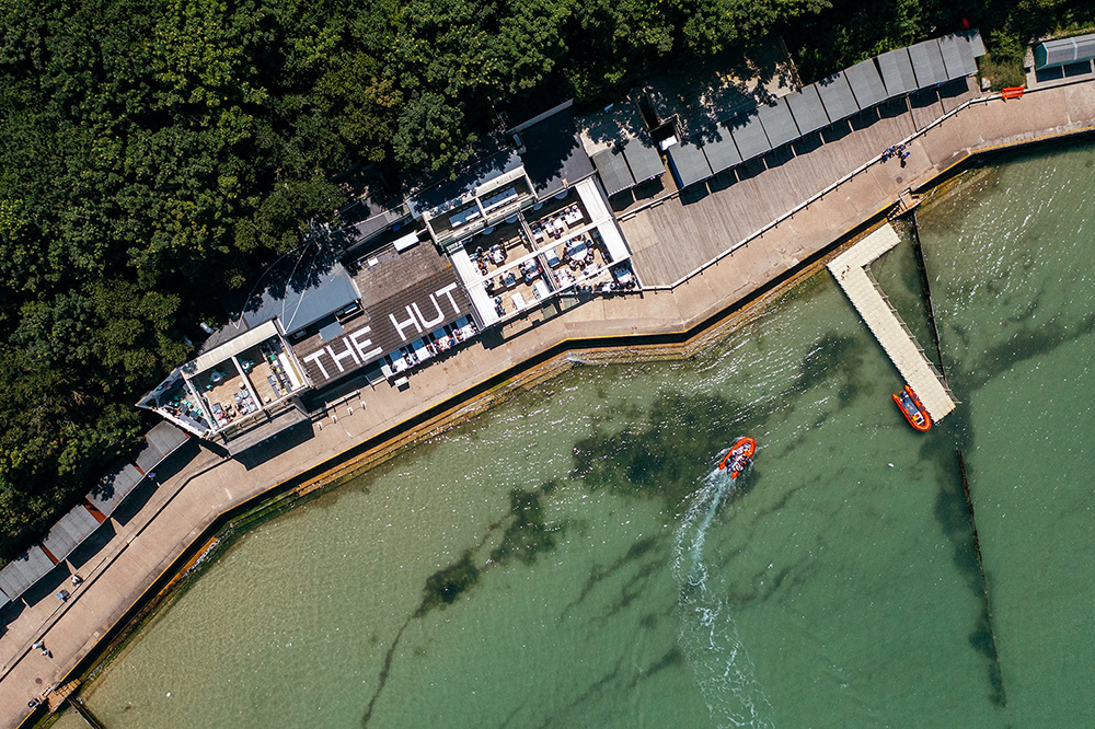 The Hut waterside restaurant on Colwell Bay, Isle of Wight, seen from above with boats at its jetty.