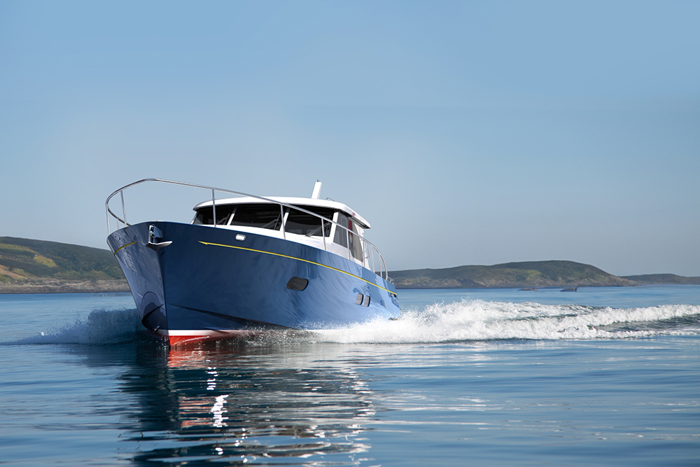 Dark blue Duchy 45 cruising at speed along a coastline, throwing up a white wake under clear skies.