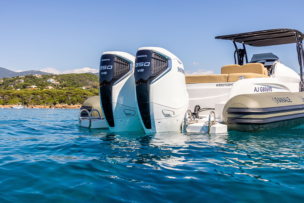 Twin Honda BF350 V8 outboards on a white RIB moored off Corsica, with a green hillside behind.