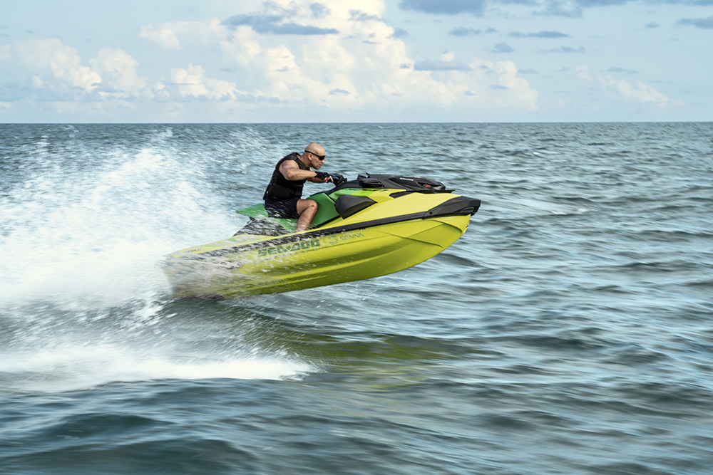 Rider launches a yellow Sea-Doo RXP-X Senna 350 personal watercraft off a wave, spray trailing behind on open water.