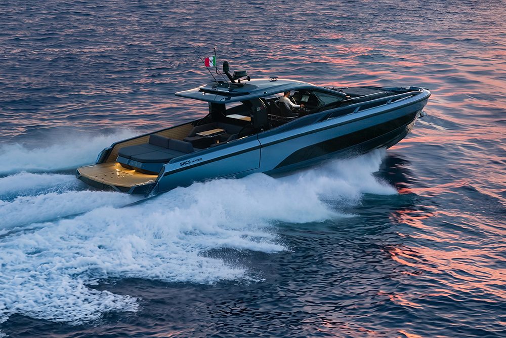 SACS Hyper 5S powers across the water at sunset, wake spraying behind its dark hull and walkaround deck.