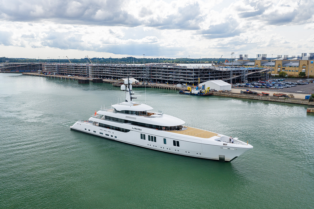 Aerial view of superyacht Lunasea cruising into Southampton docks past multi-storey car parks.
