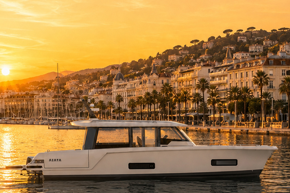AIATA Wayfinder 50 motor yacht at sunset on Cannes waterfront, with the Old Port marina and hillside villas in the background.