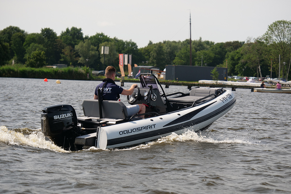 AquaSpirit RIB powered by a Suzuki outboard, driver at the helm cruising on open water, D-Tube hull visible.