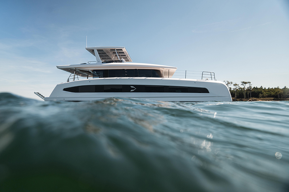 Pioneer Yachts PY60 solar-electric catamaran at sea, seen from water level, with solar panels on its flybridge hardtop.